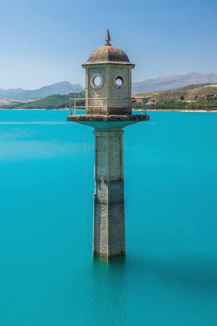 Historic Spanish tower reflected in turquoise waters of Andalusia, representing Spain's diverse beautiful landscapes